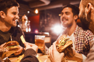 Happy friends eat burgers and drink beer at Kep's Sports Bar & Grill